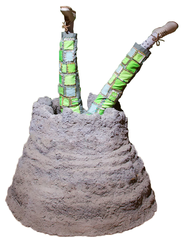 A sculpture called 'Mutant Dew'. It is a concrete mound about 3 feet tall with a hole in the middle. Two legs are coming out the hole, sticking straight in the air, 6 feet high, as though someone is falling into it. The legs have light green pants that have neon green patches on them. The feet have white shoes that have laces, soles, and bows made of sand. THe patches on the pants also have stitches made of sand. Made in 2018.